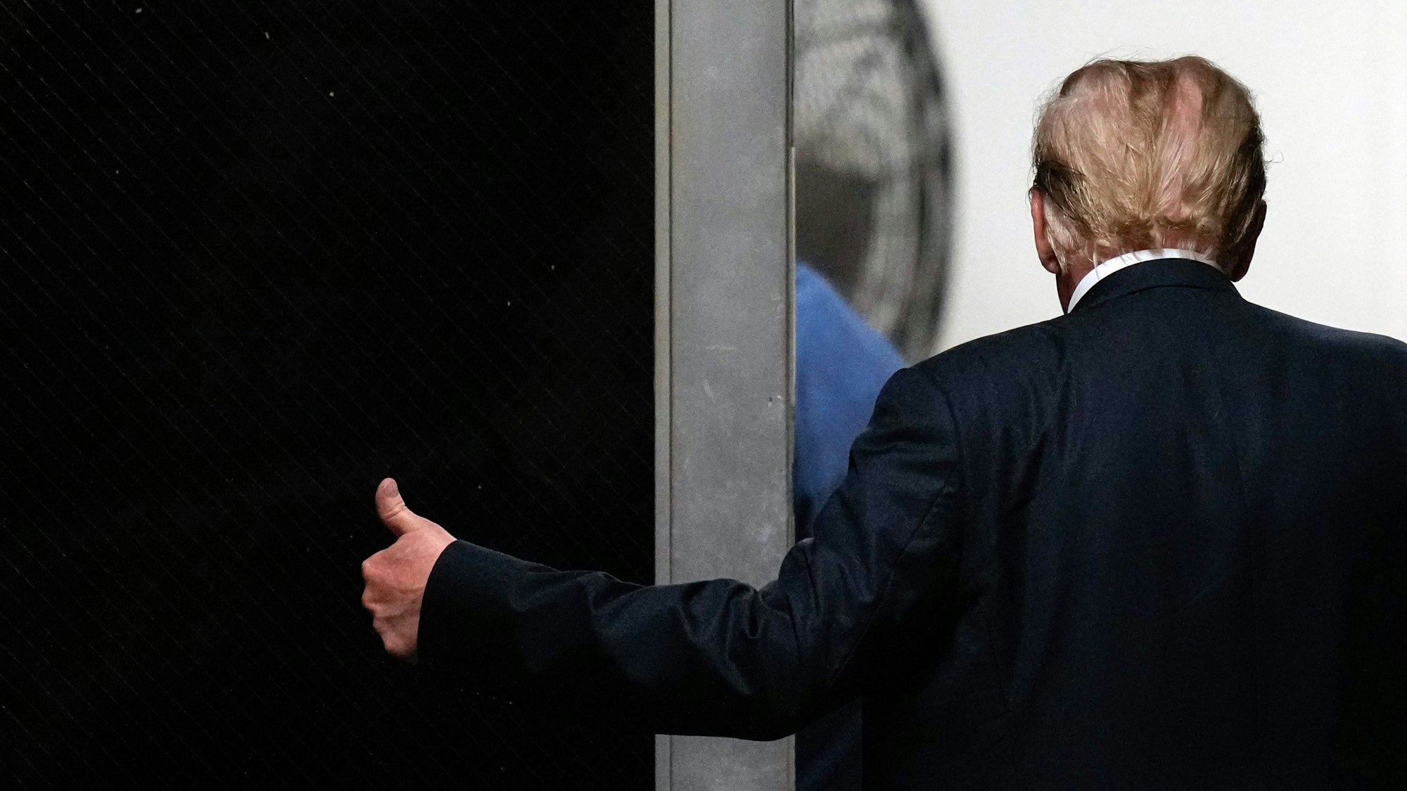 Der Ex-Präsident der USA, Donald Trump, ist von hinten zu sehen und gibt einen Daumen hoch.