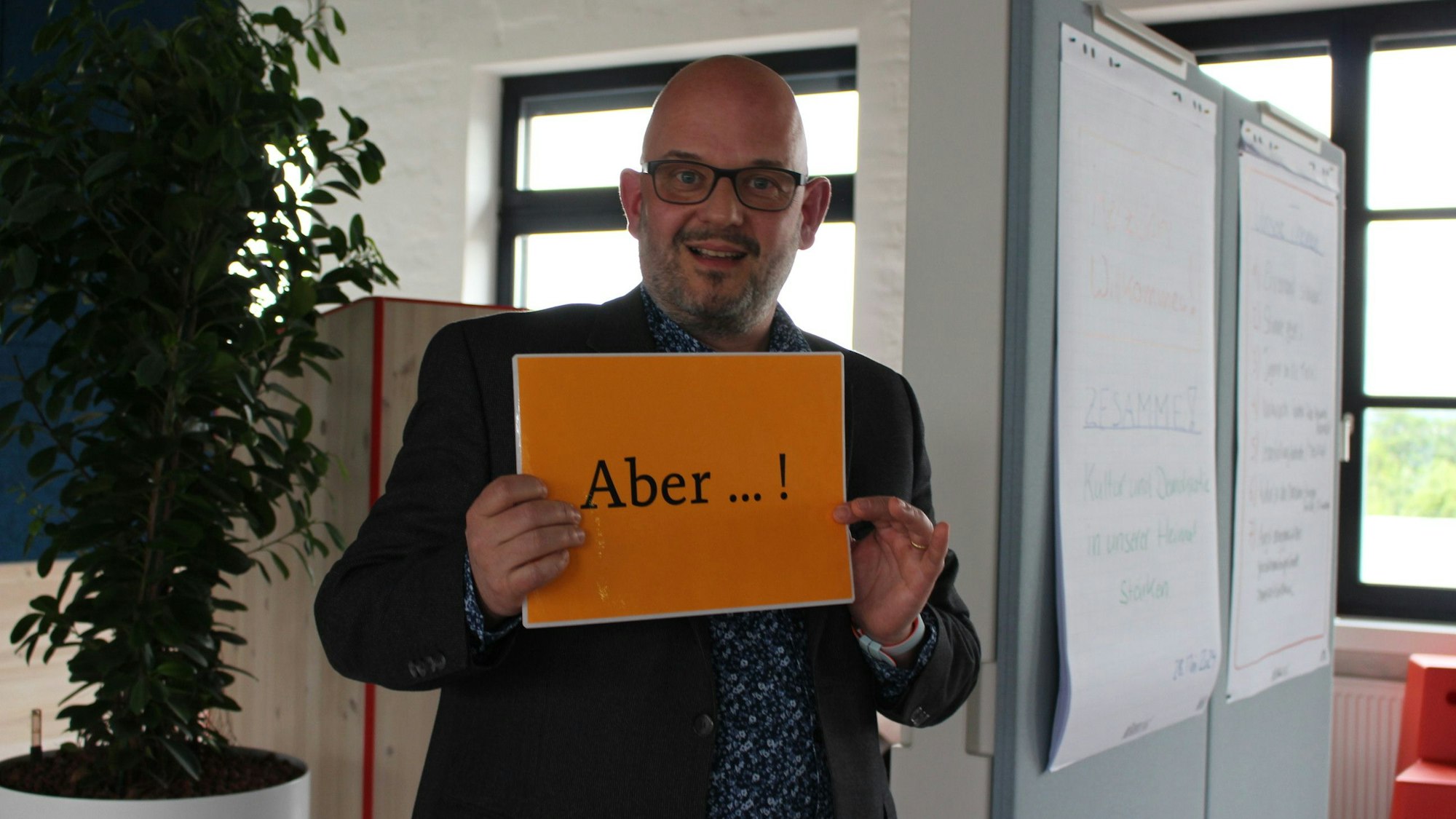 Tim Becker zeigt ein Schild mit der Aufschrift „Aber“.