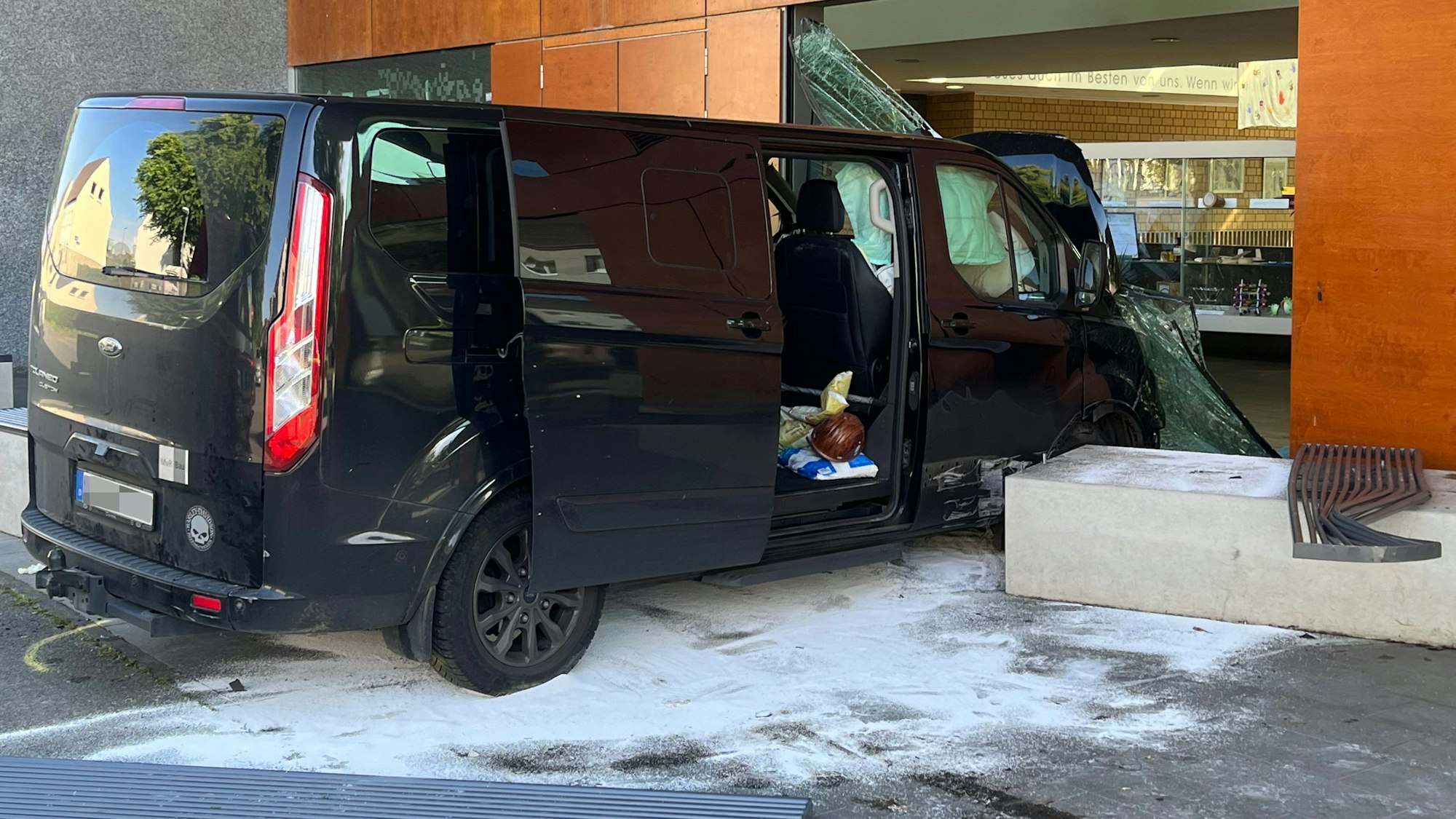 Ein Transporter steht in der zerstörten Glasfront eines Schulgebäudes.