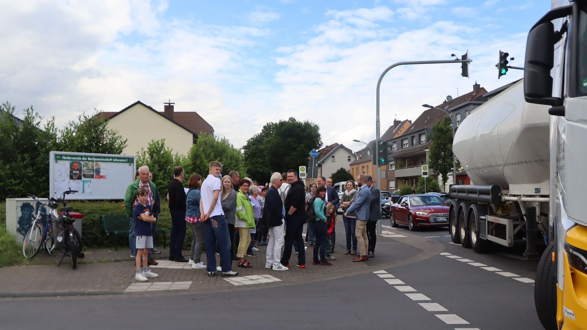 Eine Gruppe von Menschen steht an einer Kreuzung, ein großer Lastwagen biegt gerade ab.