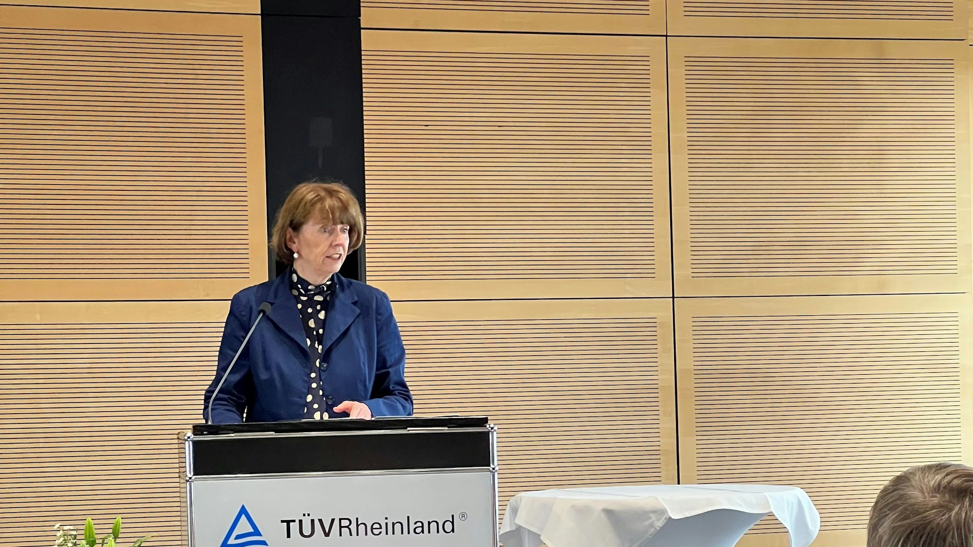 Eine Frau im blauen Blazer steht an einem Rednerpult.