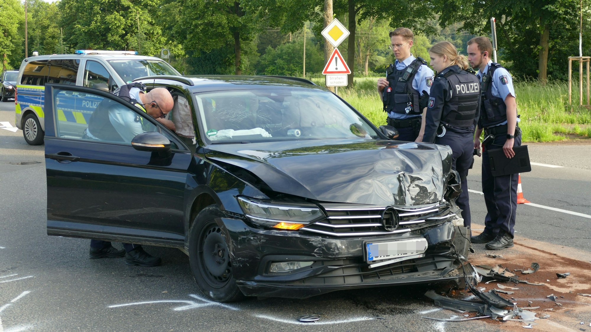 Polizistinnen und Polizisten stehen um ein kaputtes Auto herum.