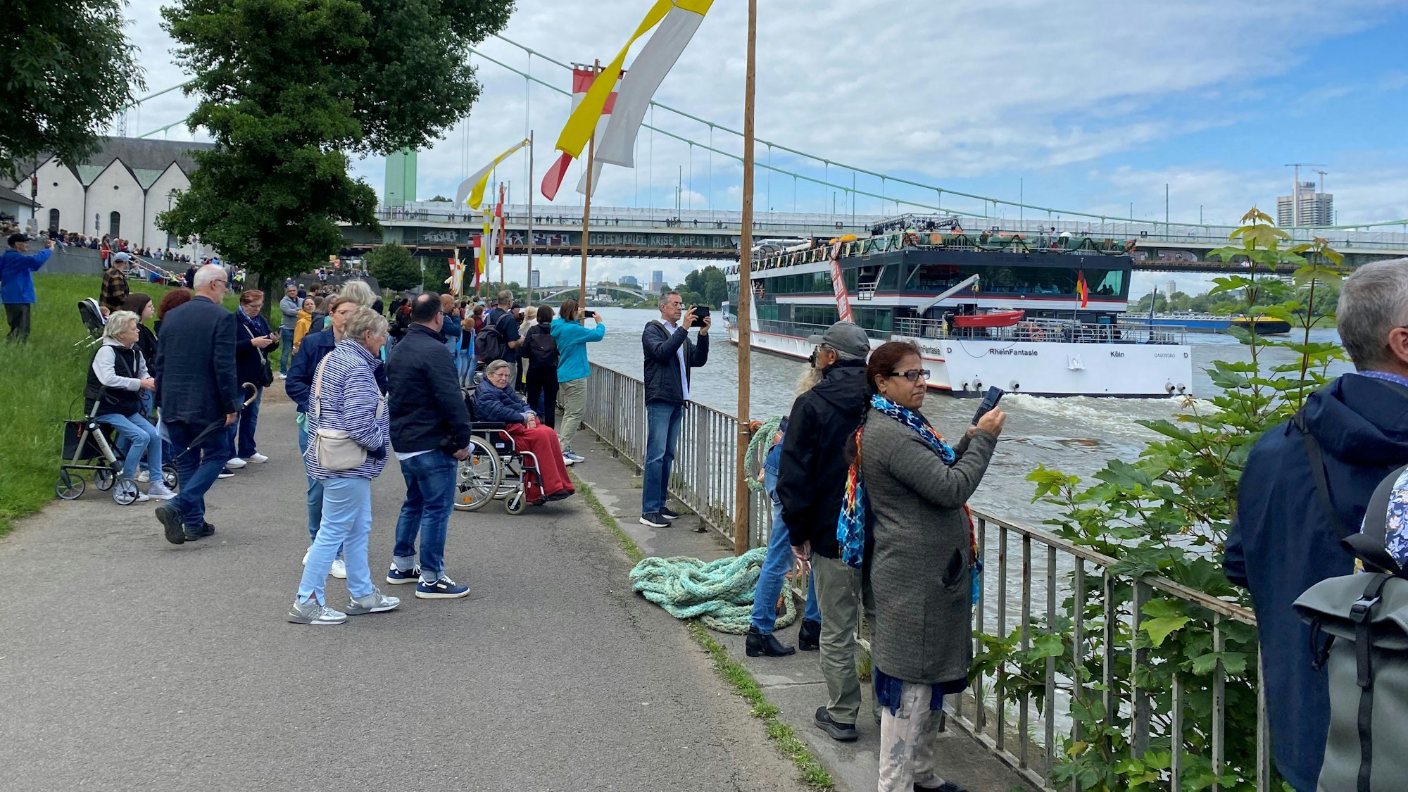 Menschen beobachten die MS RheinFantasie nach dem Ablegen in Köln-Mülheim.