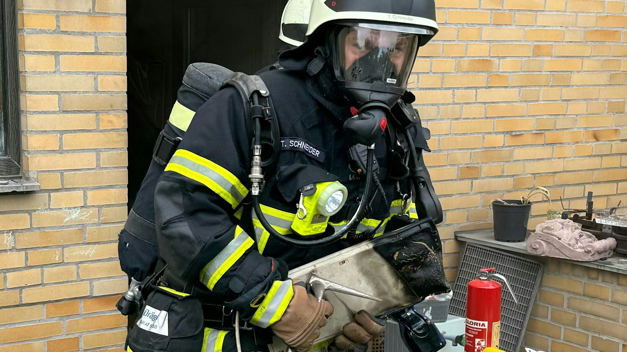 Ein Feuerwehrmann trägt eine verkohlte Computer-Tastatur aus einem Haus in Erftstadt.