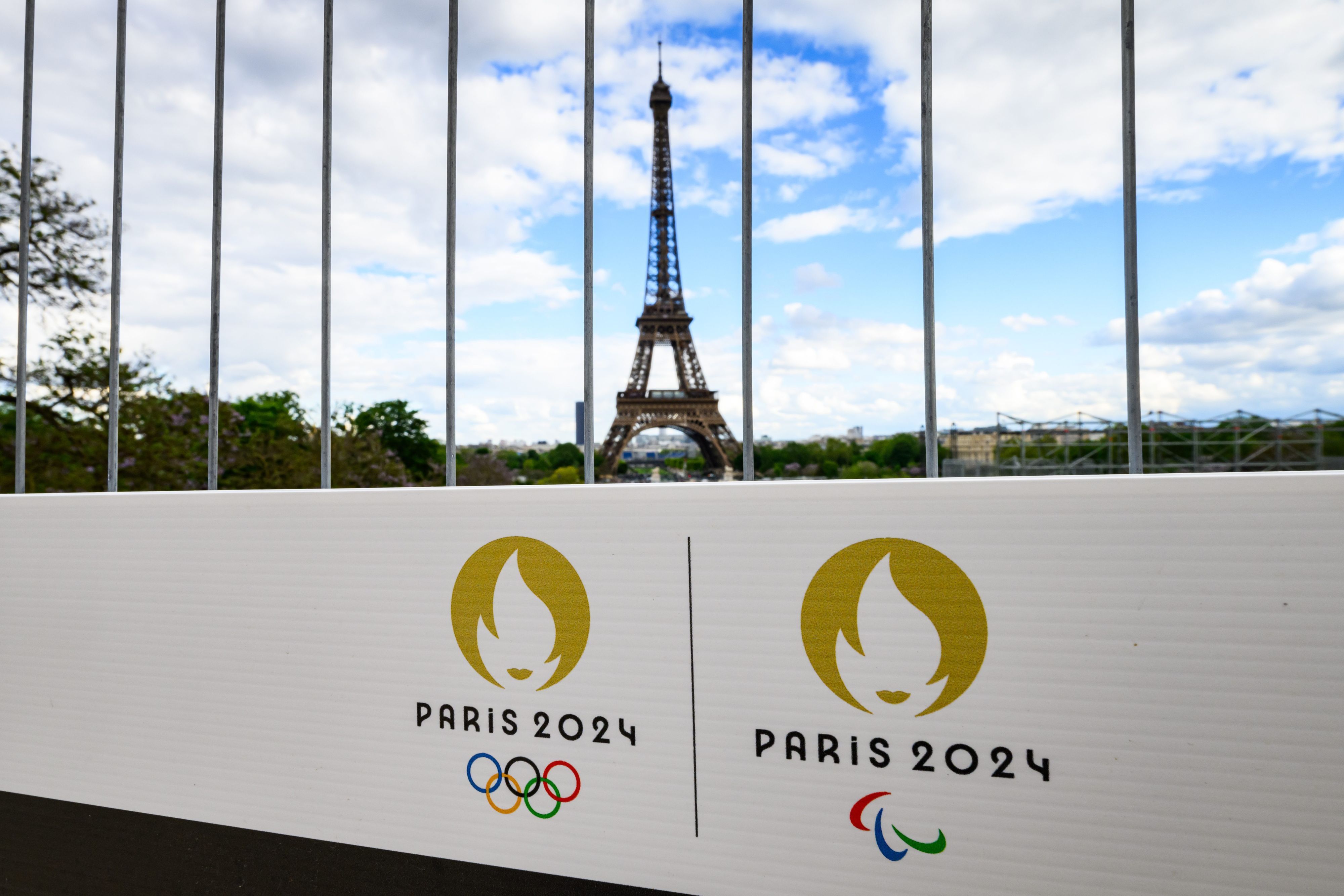 Die Olympischen Ringe und das Logo der Paralympischen Spiele sind auf einem Schild an einem Bauzaun vor dem Eiffelturm zu sehen. (Archivbild)