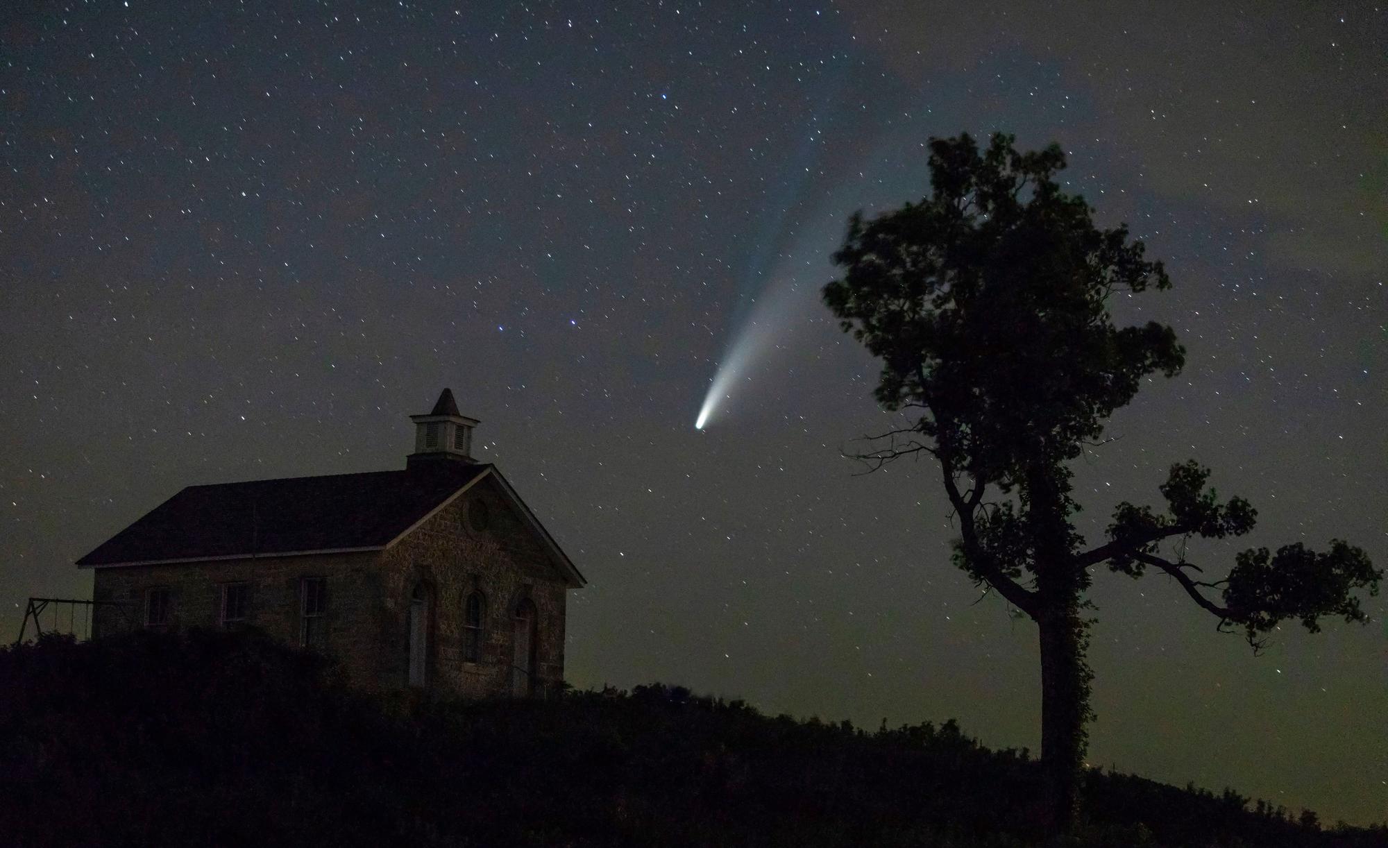 Komet Neowise oder C/2020 F3 ist am Nachthimmel über dem US-Reservat «Tallgrass National Prairie Preserve» zu sehen. Im Vordergrund des Fotos steht links ein Haus und rechts ein Baum.