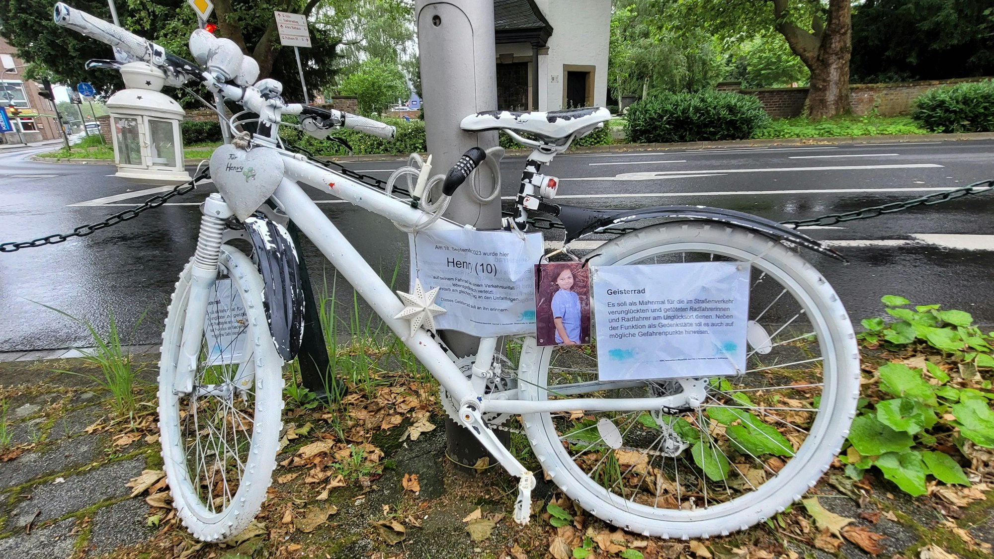 Ein weiß lackiertes Fahrrad ist an einem Laternenmast befestigt.