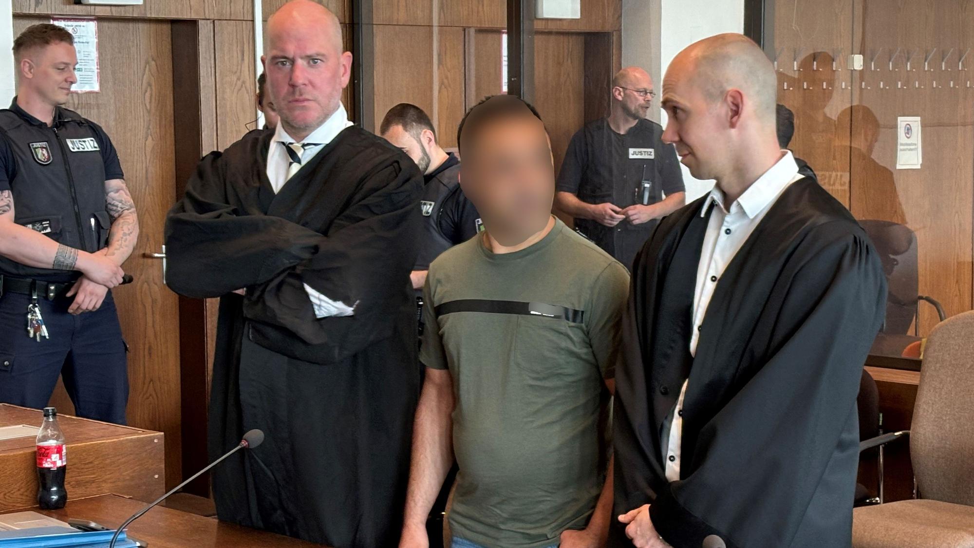 Ein Angeklagter steht zwischen seinen Anwälten vor dem Kölner Landgericht.