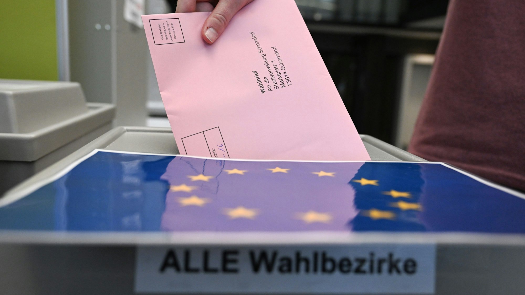 Ein Wahlbrief mit einem Stimmzettel für die Europawahl wird im Rathaus in einem Wahllokal für die Briefwahl in eine Wahlurne gesteckt.