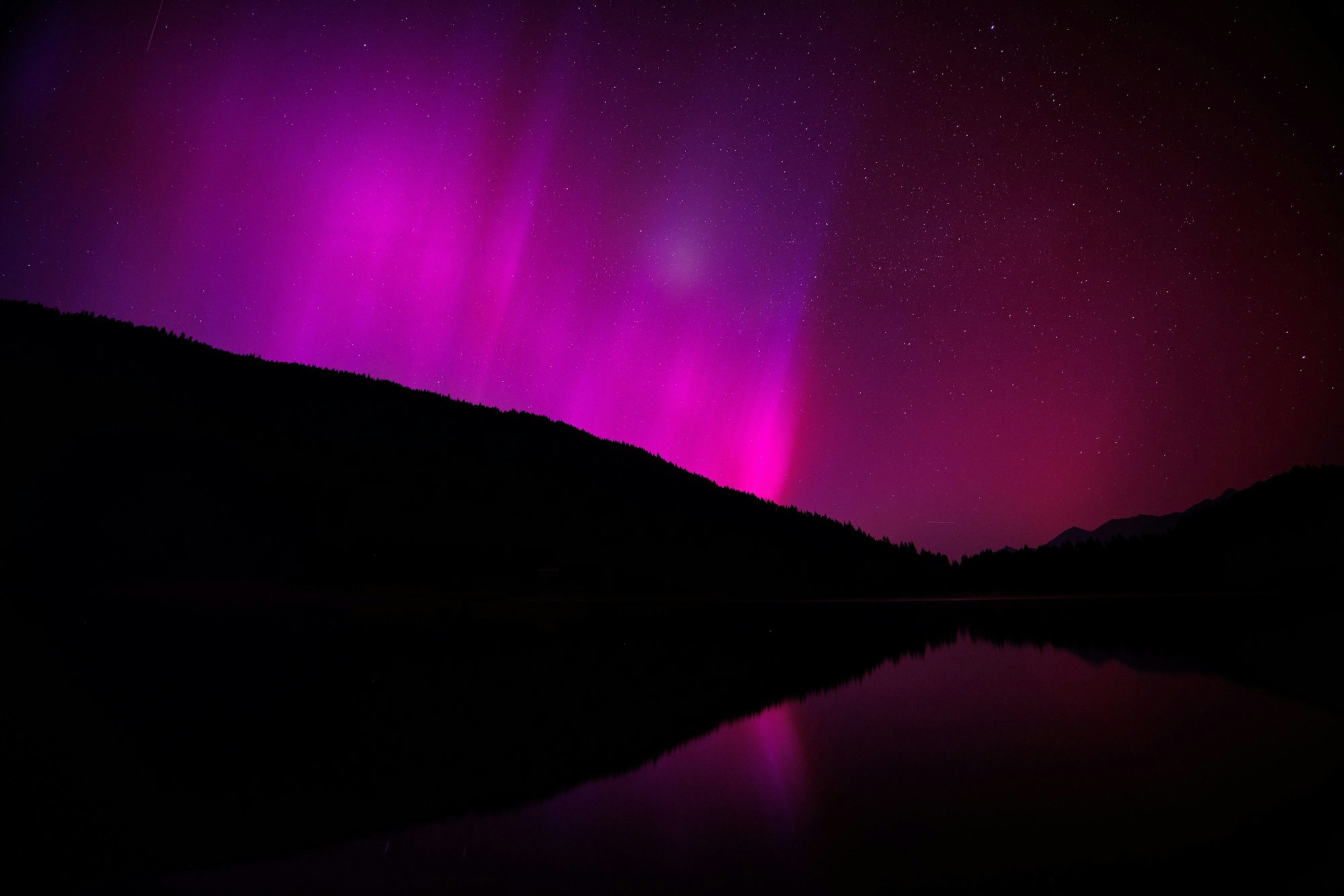 Polarlichter (Aurora borealis) leuchten am nächtlichen Himmel über dem Wagenbrüchsee in Bayern.