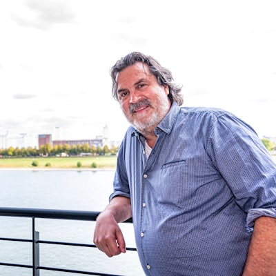Thomas Reis steht auf seinem Balkon, hinter ihm ist der Rhein zu sehen.