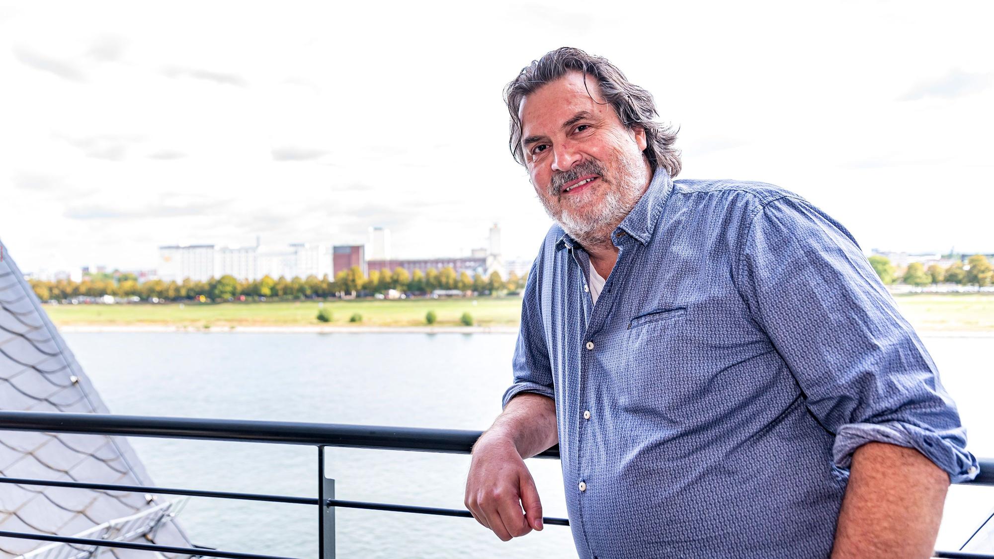 Thomas Reis lehnt am Geländer seines Balkons, hinter ihm ist der Rhein zu sehen.