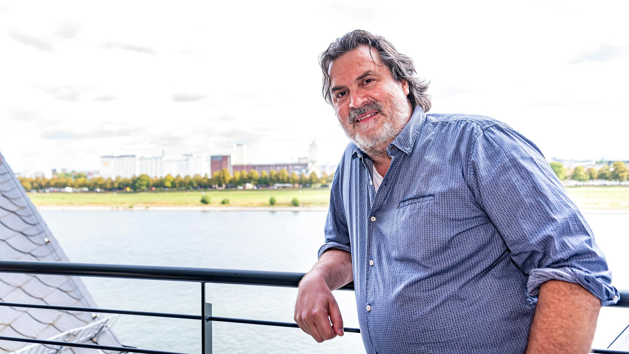 Thomas Reis lehnt am Geländer seines Balkons, hinter ihm ist der Rhein zu sehen.