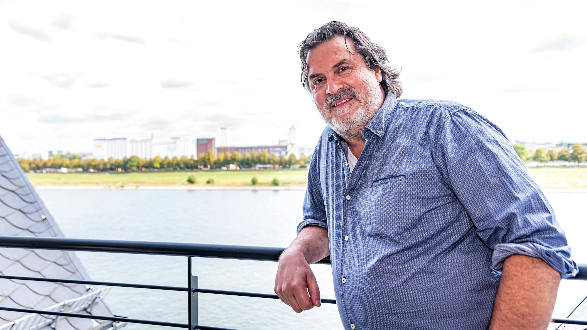 Thomas Reis steht auf seinem Balkon, hinter ihm ist der Rhein zu sehen.