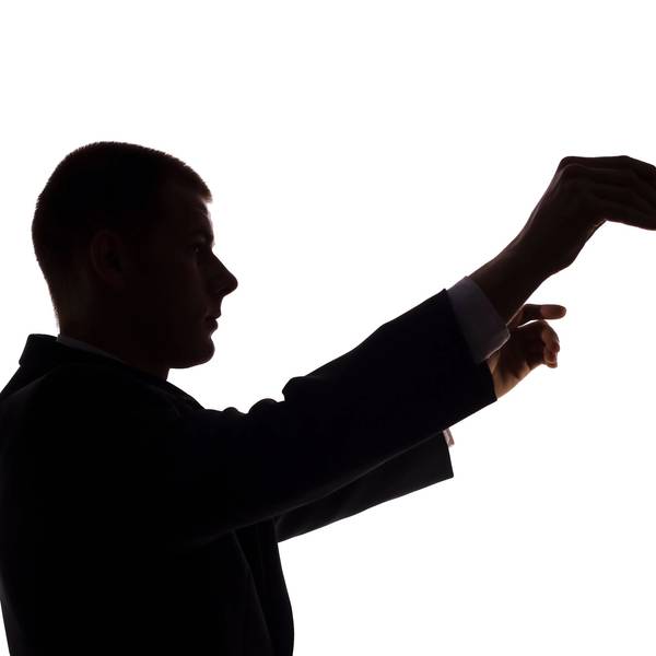 Die Silhouette eines Dirigenten vor weißem Hintergrund.