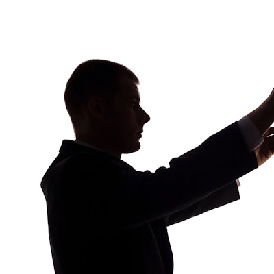 Die Silhouette eines Dirigenten vor weißem Hintergrund.