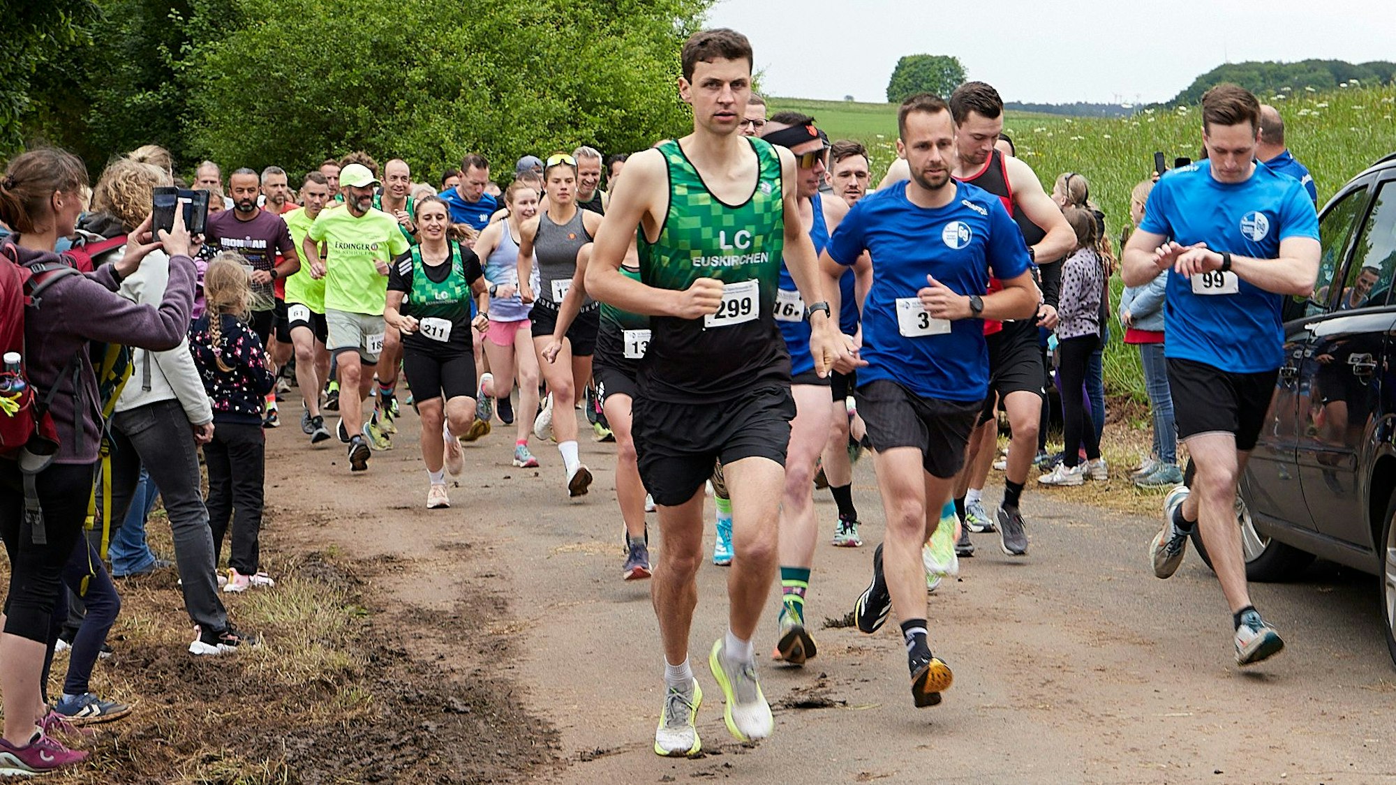 Sportler laufen in verschiedenfarbiger Laufbekleidung über einen asphaltierten Weg – allen voran: Markus Seidenfaden.