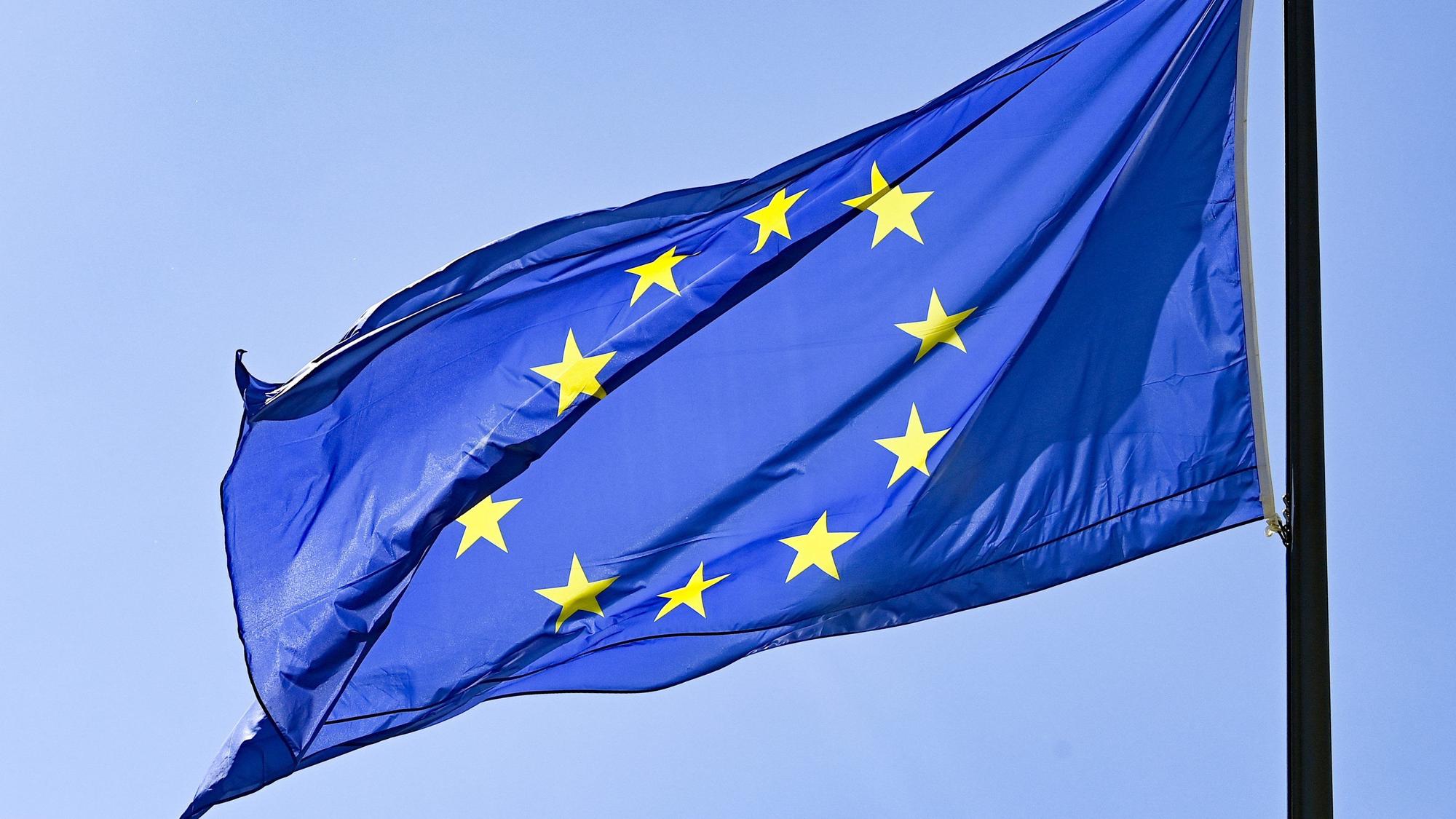 Eine Europaflagge weht vor blauem Himmel.