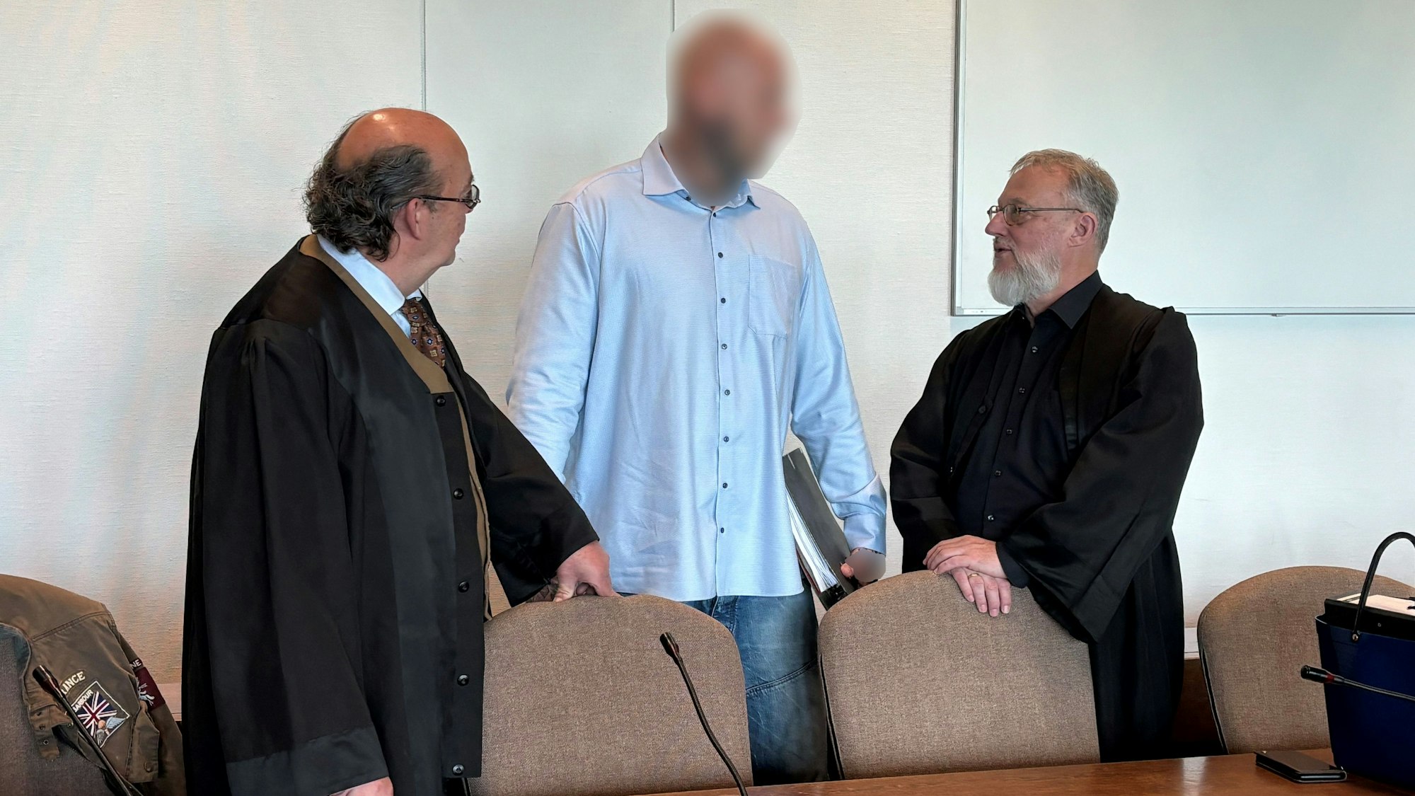 Verteidiger Uwe Krechel, der angeklagte 39-Jährige und Verteidiger Thomas Ohm stehen beim Prozessauftakt um einen Goldraub in Rösrath am 15. Mai 2024 in einem Gerichtssaal des Kölner Landgerichts.