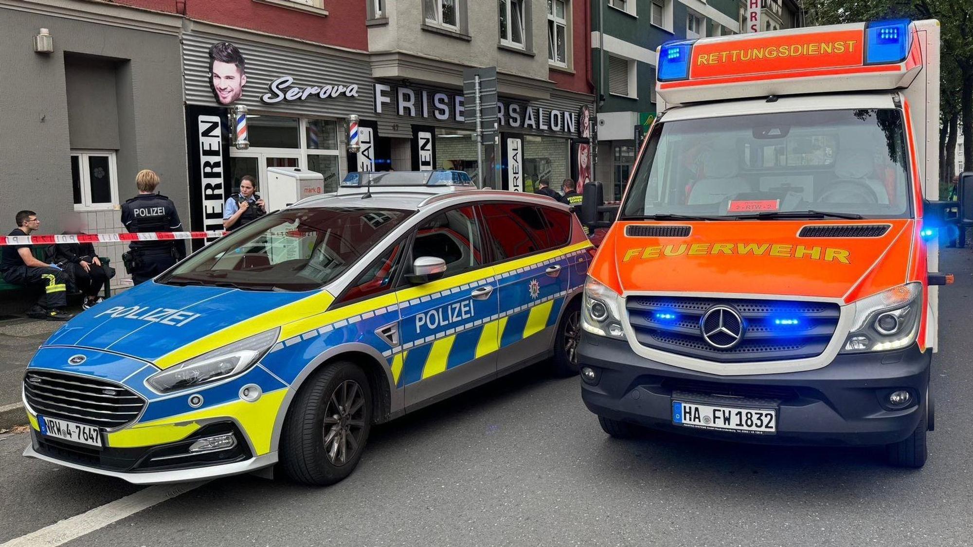 Ein Einsatzfahrzeug der Polizei und ein Rettungswagen der Feuerwehr stehen vor einem Friseursalon.