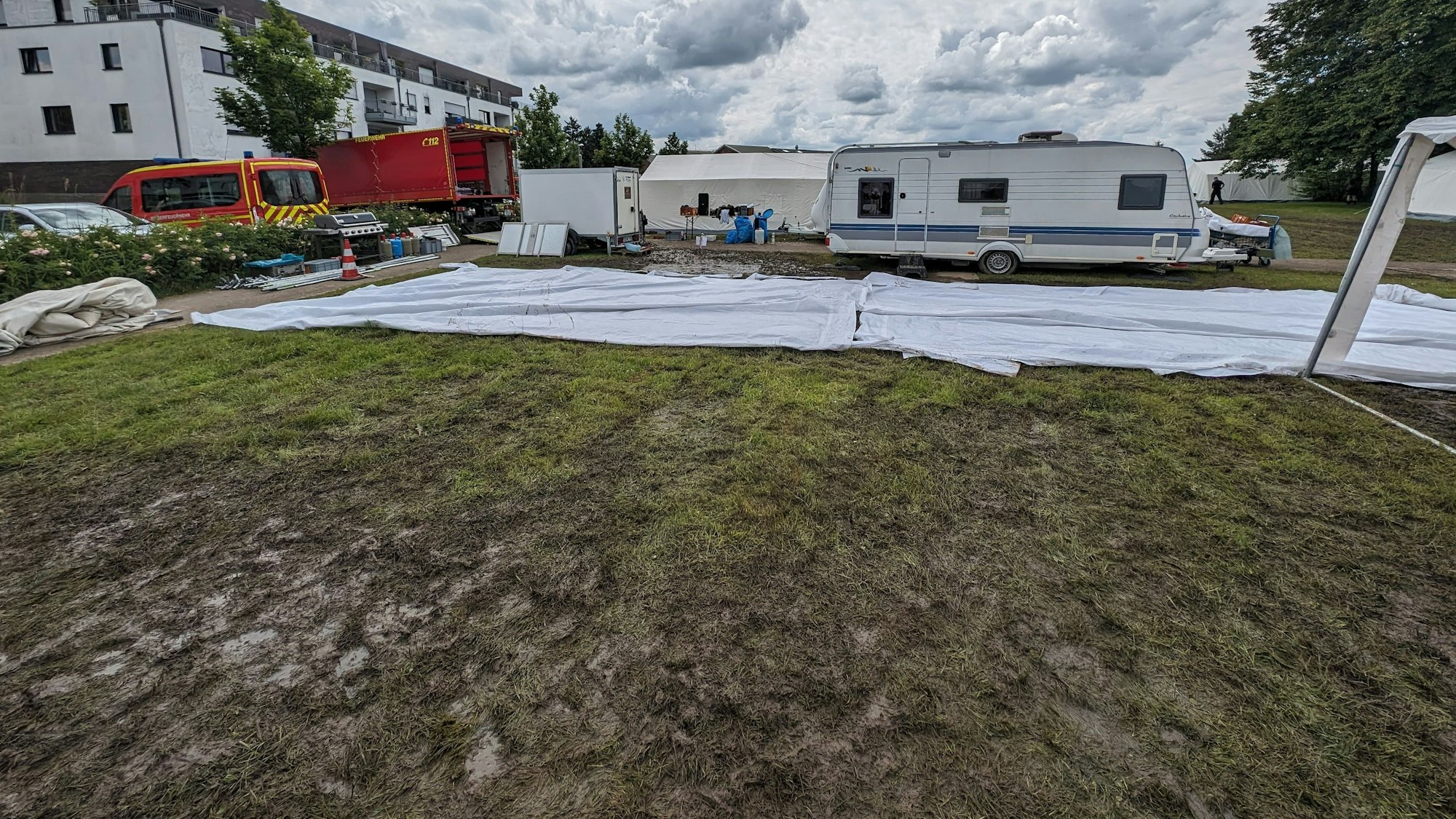 Ein Zelt steht im Matsch, auf dem Boden liegen Stahlplatten, die auch bereits mit Matsch bedeckt sind.
