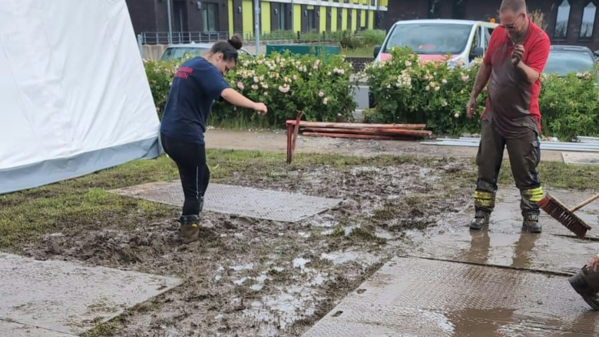 Ein Zelt steht im Matsch, auf dem Boden liegen Stahlplatten, die auch bereits mit Matsch bedeckt sind.