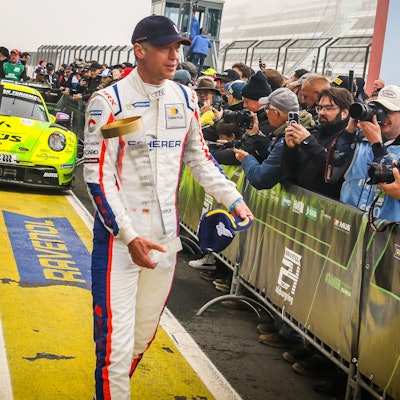 Rennfahrer Frank Stippler steht mit einem Pokal vor den Fotografen.