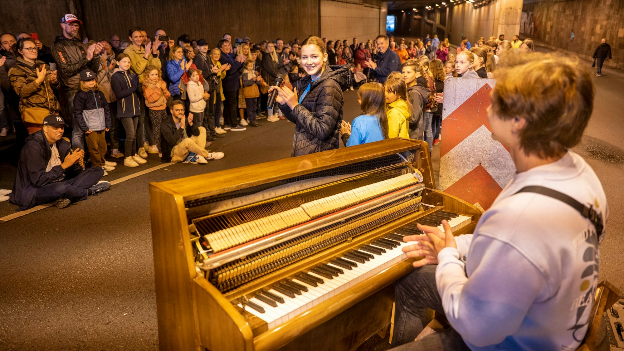In einem Tunnel steht ein Klavier, Menschen stehen am Rand und hören zu.