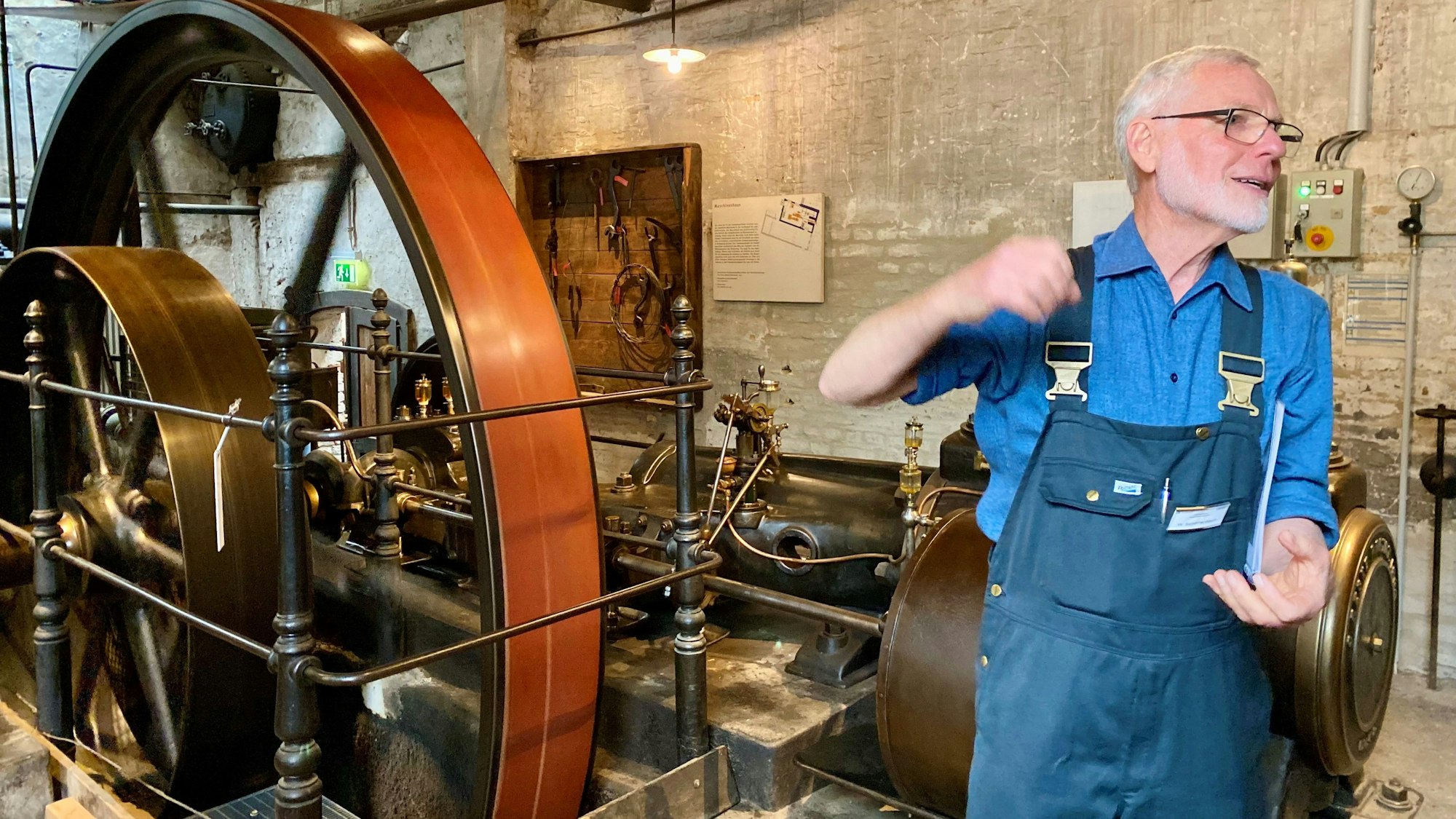 Ein Mann im Blaumann erklärt, wie Textilien hergestellt werden.