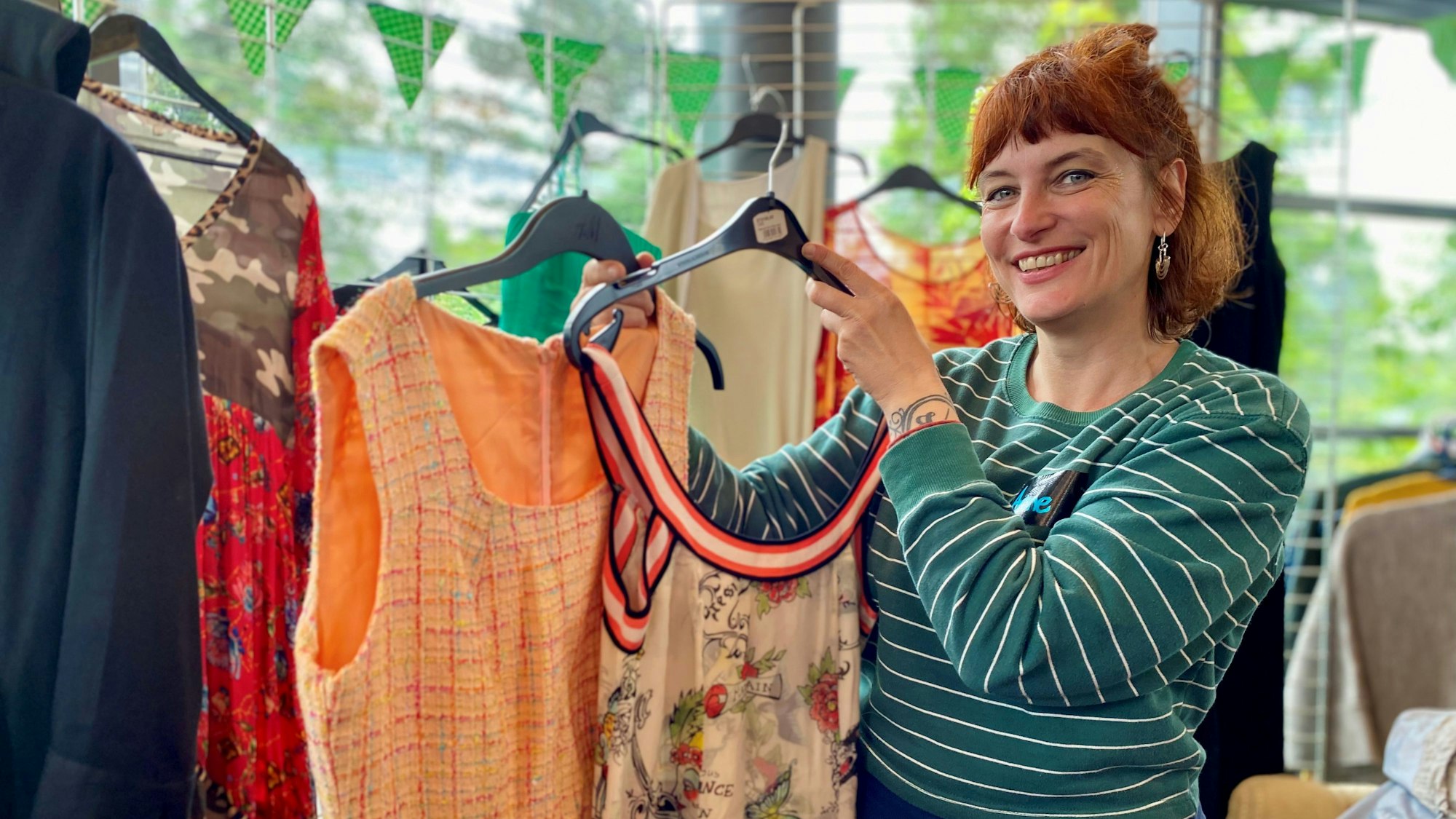Anne Dockter-Biggs posiert mit zwei Kleidern.