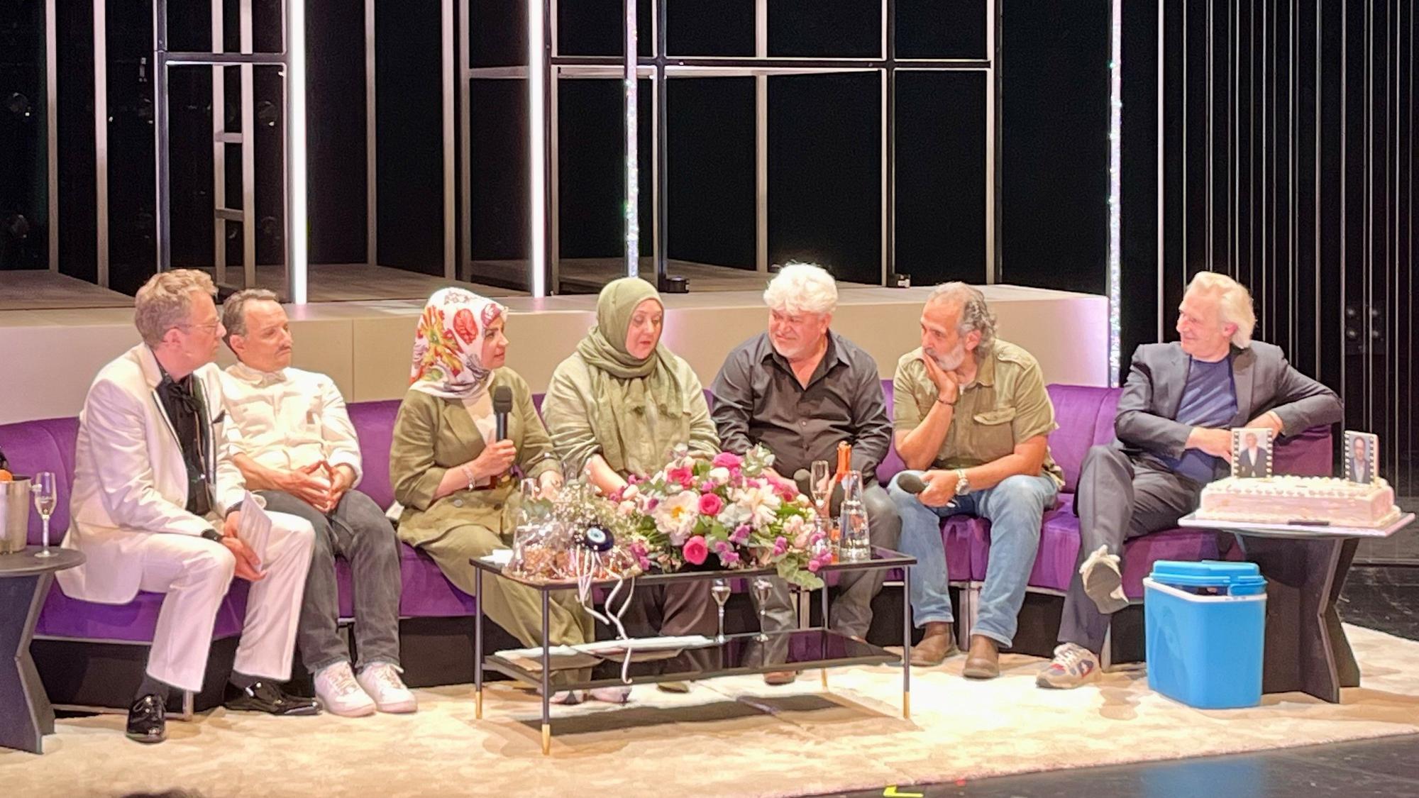 Auf einem langen lila Sofa sitzen (von links nach rechts): Thomas Laue, Stefko Hanushevsky, Meral Sahin, Ismet Büyük, Ayfer Sentürl Demir, Kutlu Yurtseven und Stefan Bachmann