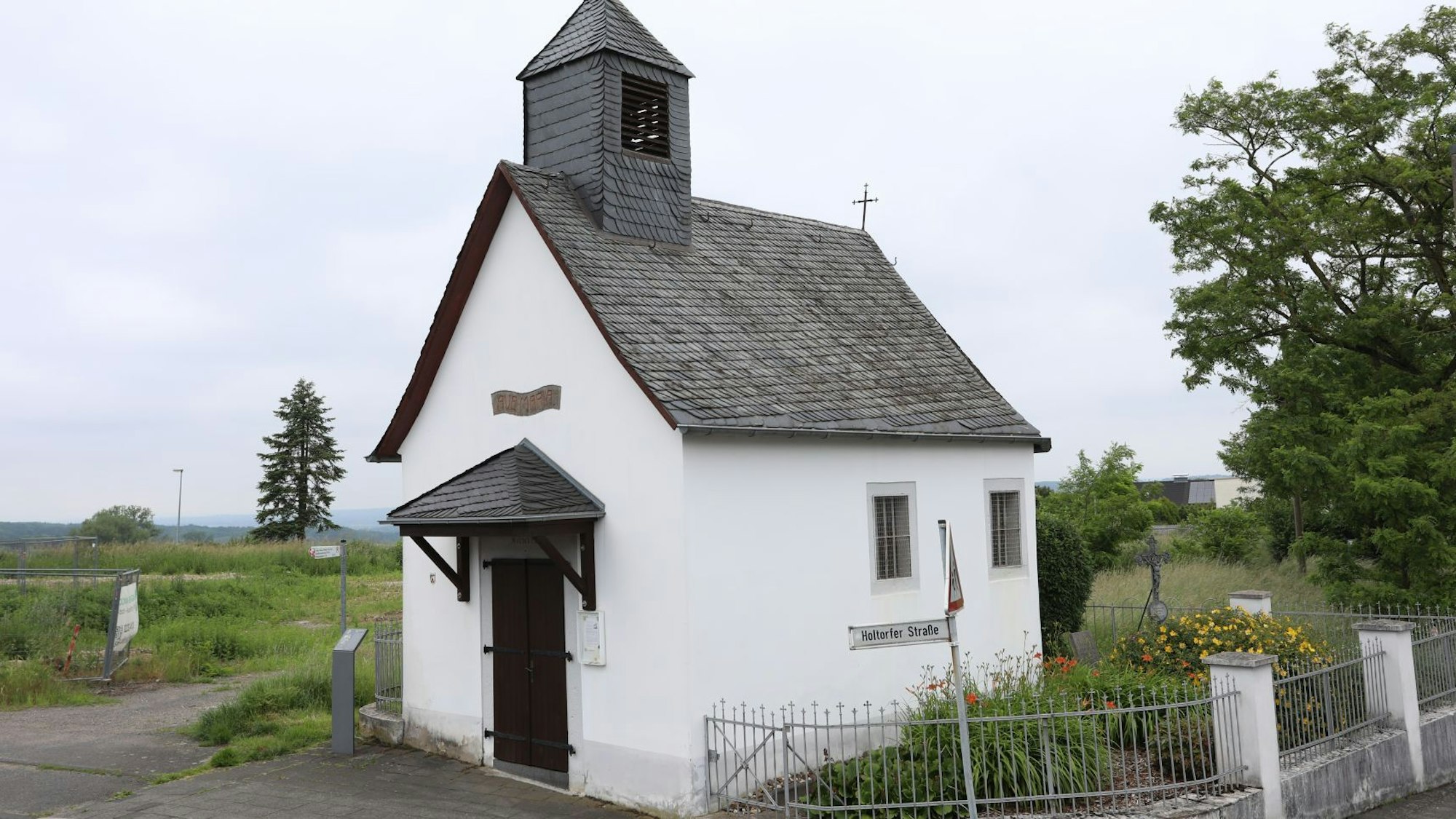Eine kleine Kapelle mit weißer Fassade und einem mit Schiefer gedeckten Dach.