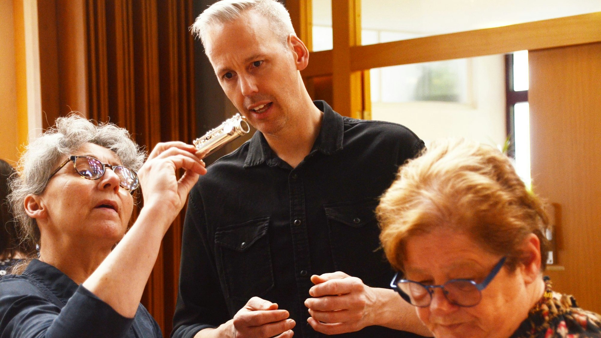 Eine Frau zeigt einem Mann ein Element einer Querflöte.