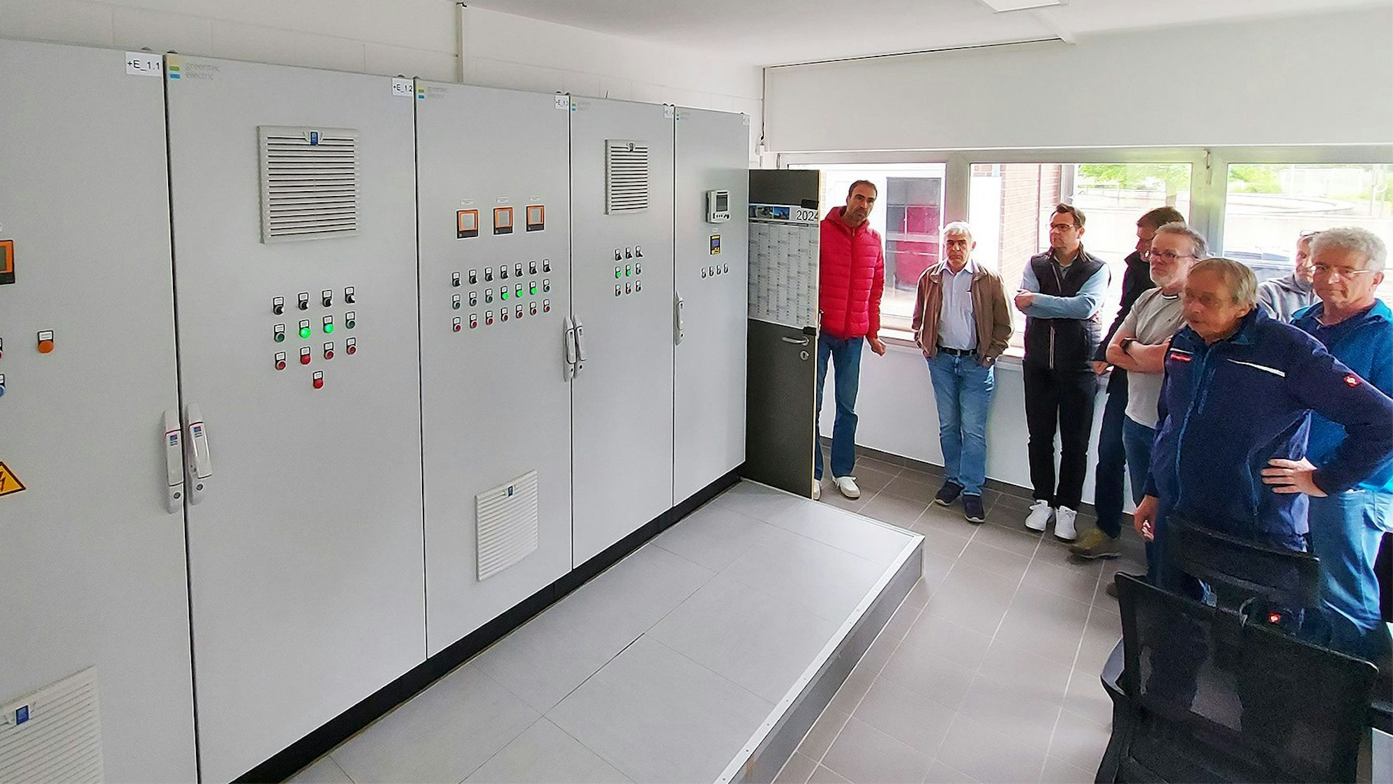 Mehrere Männer begutachten die Schaltanlage im Betriebsgebäude der Kläranlage Kronenburg.