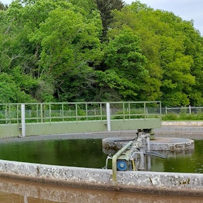 Mehrere Männer stehen auf der Schieberbrücke über dem Belebungsbecken der Kläranlage in Kronenburg.
