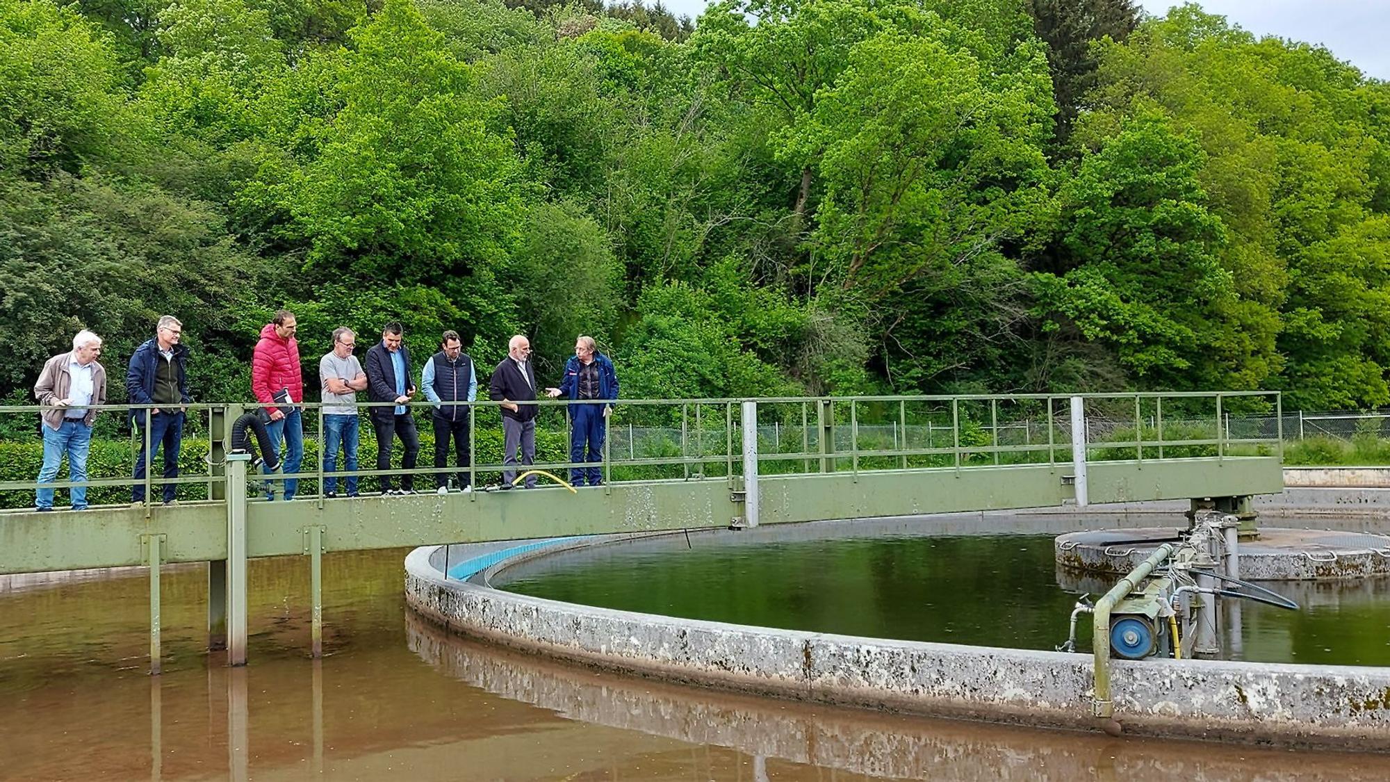 Mehrere Männer stehen auf der Schieberbrücke über dem Belebungsbecken der Kläranlage in Kronenburg.