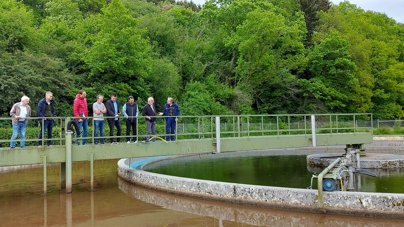 Mehrere Männer stehen auf der Schieberbrücke über dem Belebungsbecken der Kläranlage in Kronenburg.