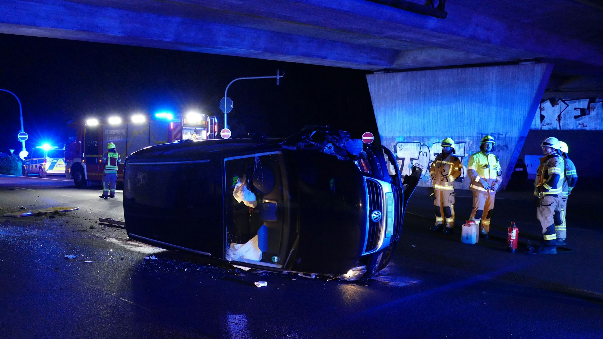 Ein Auto liegt auf der Seite, dahinter stehen Feuerwehrleute.