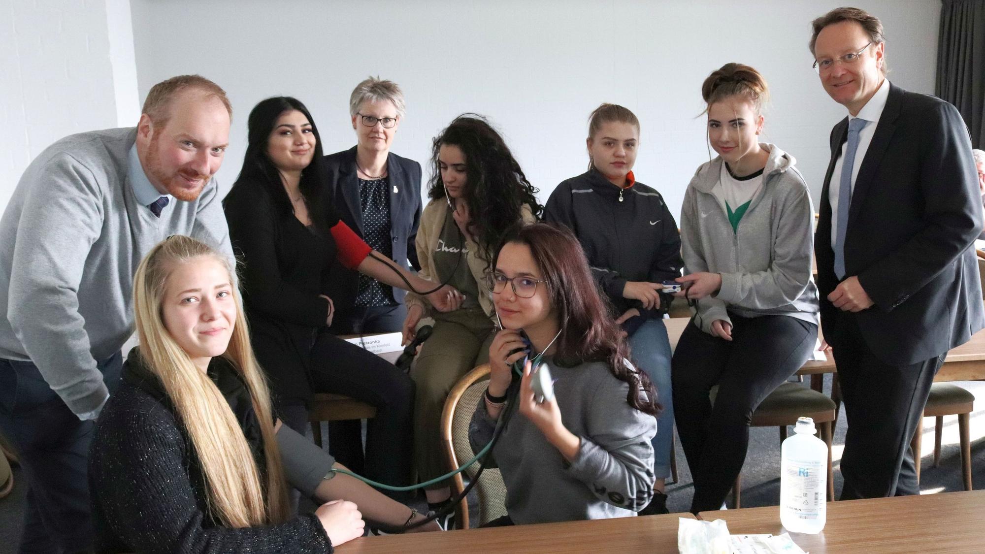 Die Teilnehmern eines dreitägige Praxiskurses sitzen mit Vertretern von Handwerk und Berufsschulen in einem Klassenraum in Bergisch Gladbach.
