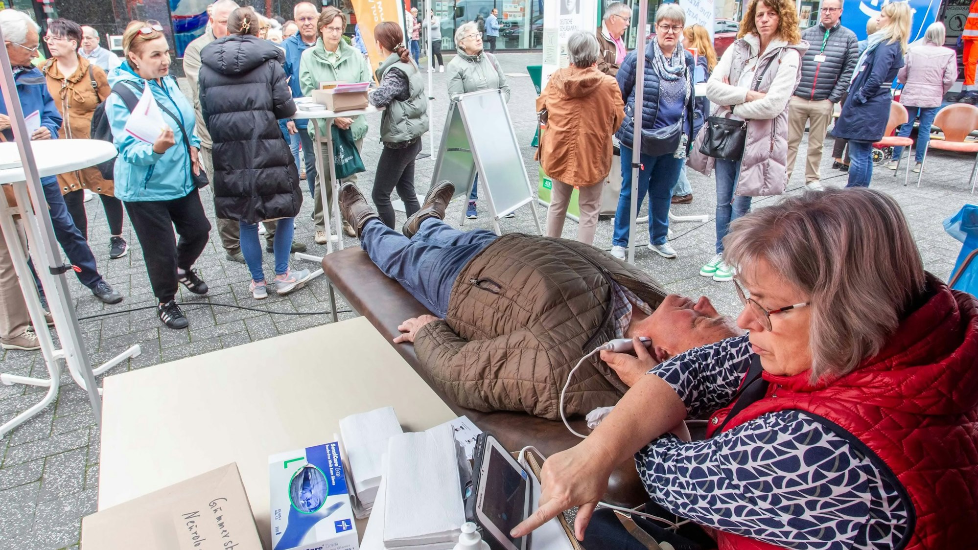 Foto einer Untersuchung eines Mannes am Hals in einer Fußgängerzone