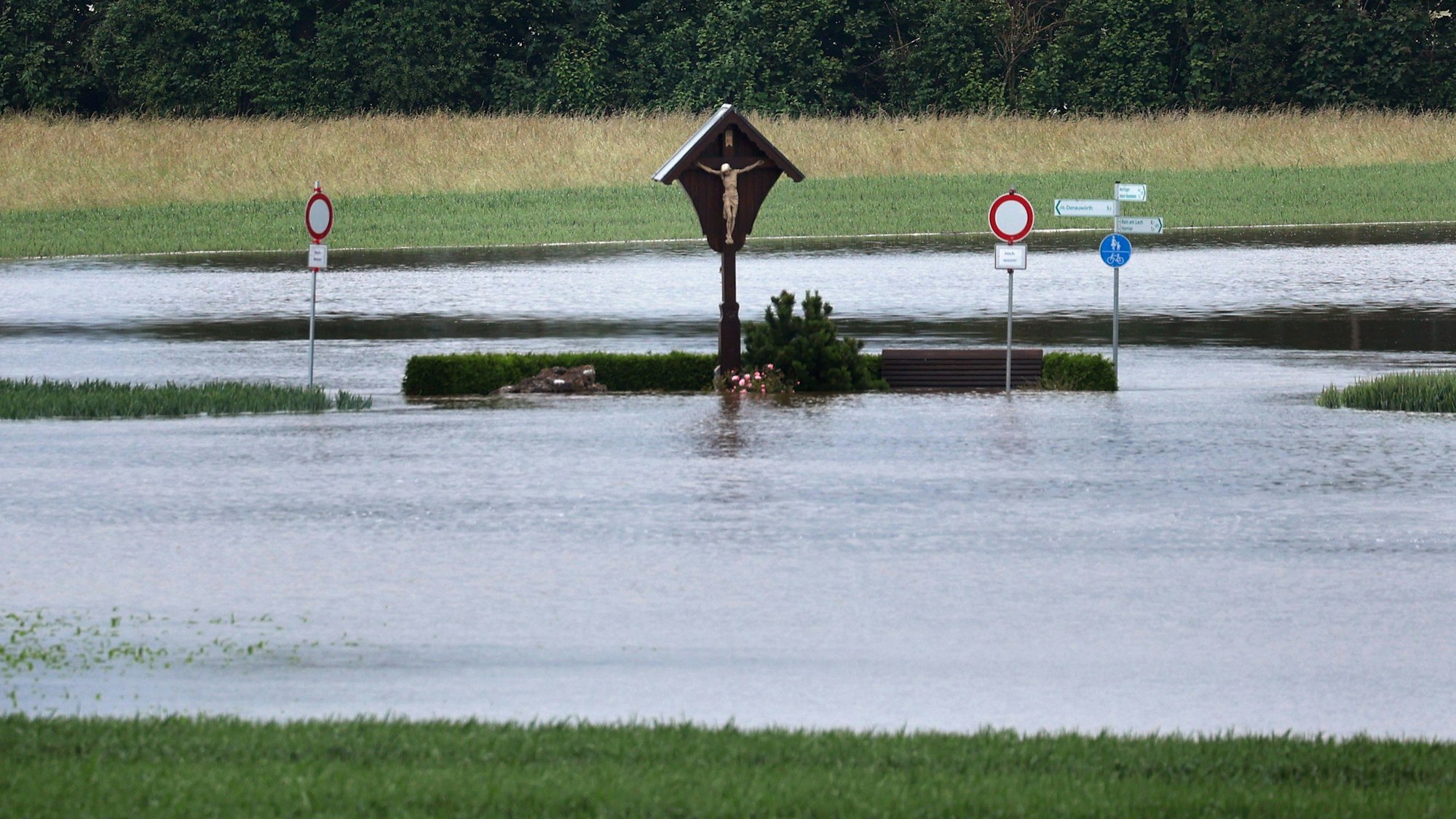 Ein Wegkreuz steht am Montag in der vom Hochwasser überfluteten Landschaft nahe Asbach-Bäumenheim in Bayern.