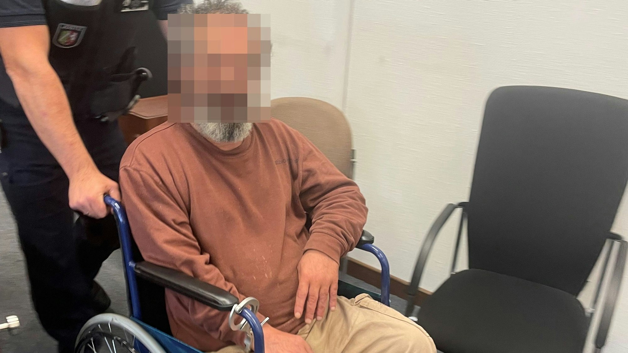 Der Angeklagte war mit Handschellen an den Rollstuhl gekettet, wurde so in den Gerichtssaal gebracht.