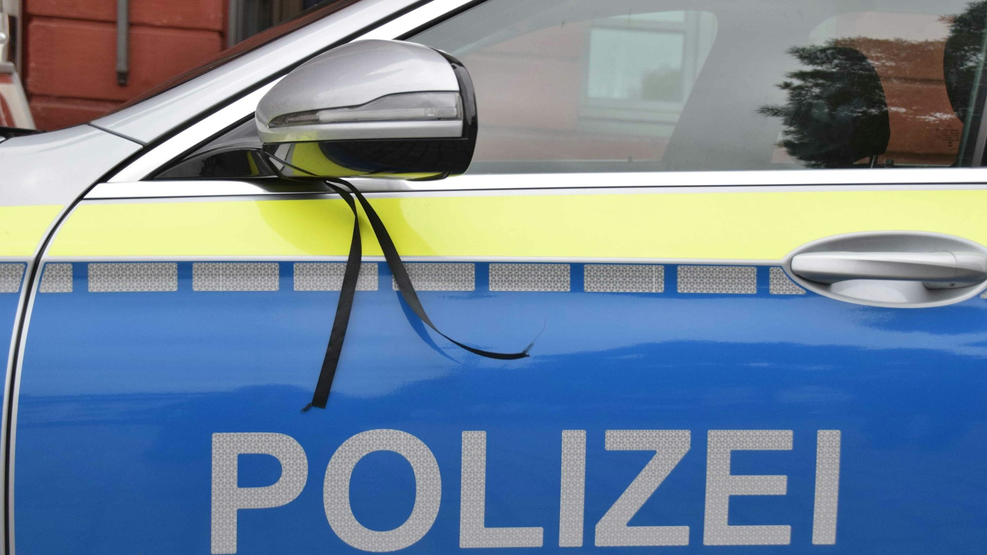 Ein schwarzes Band ist als Trauerflor an einem PKW der Polizei angebracht