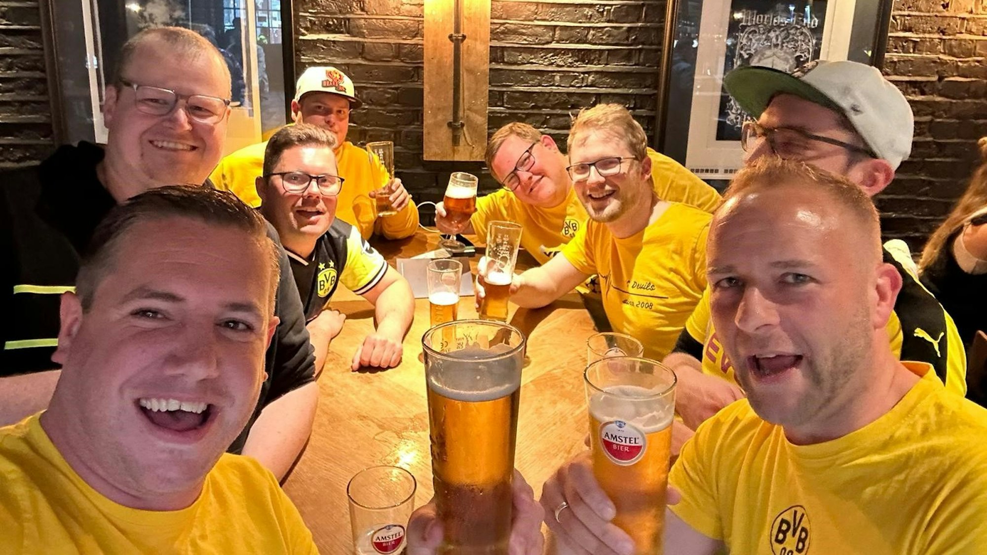 Die Dortmund-Fans sitzen in einem Pub und halten Biergläser in der Hand.