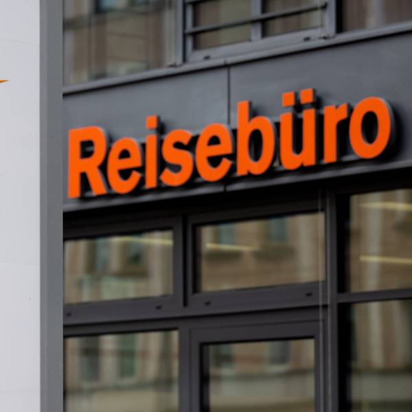 Das Logo des Reiseveranstalter FTI (FTI Group) steht an der Firmenzentrale vor einem Reisebüro.