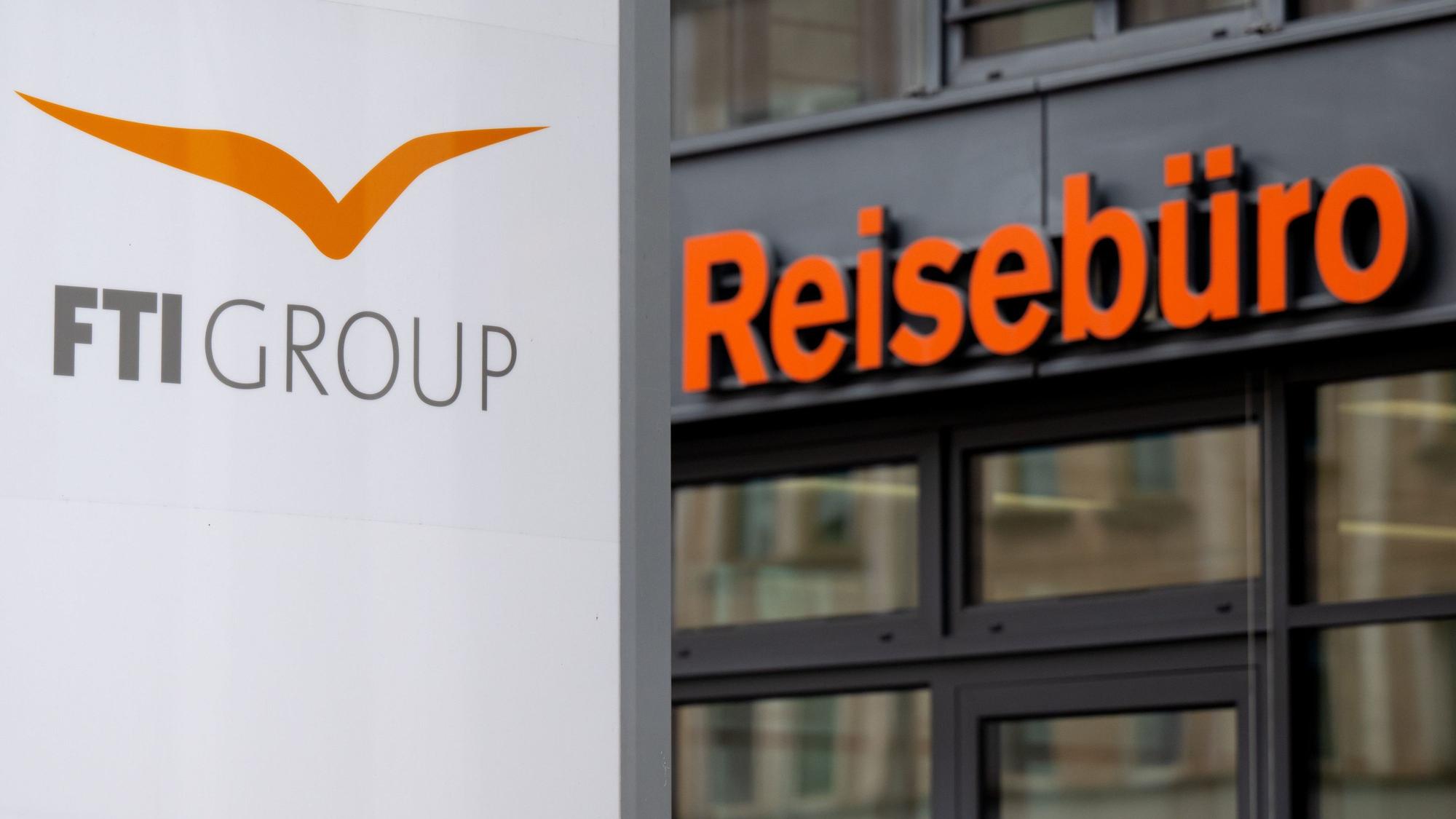 Das Logo des Reiseveranstalter FTI (FTI Group) steht an der Firmenzentrale vor einem Reisebüro.