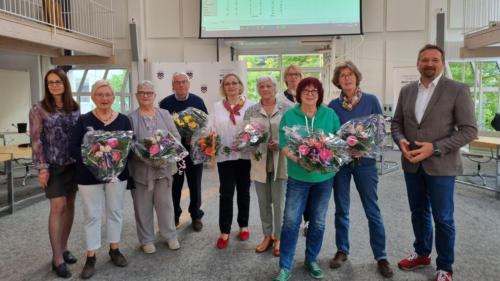 Eine Gruppe von Männern und Frauen, die meisten halten Blumensträuße in den Händen.