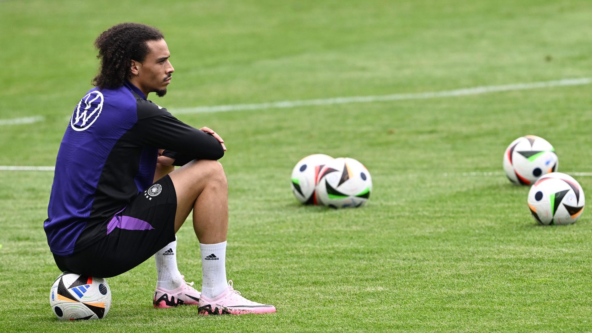 Leroy Sané sitzt auf einem Ball und beobachtet die Spieler beim Training.