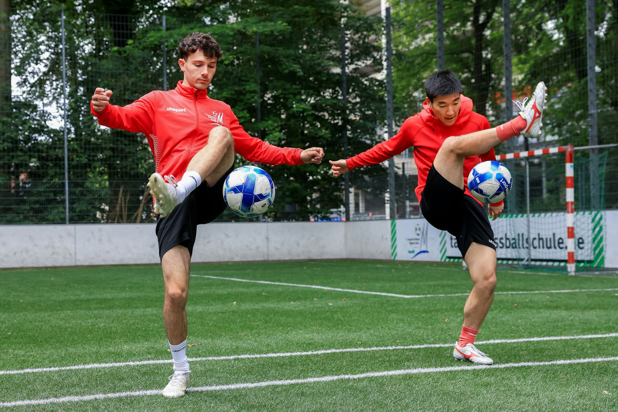 Die Trainer Kei Tomonaga und Moritz Mattheis der Jugendfußballschule Köln zeigen Balltricks.
Im Bild wird der Trick „Around the world“ auf einem Kunstrasenplatz gezeigt.