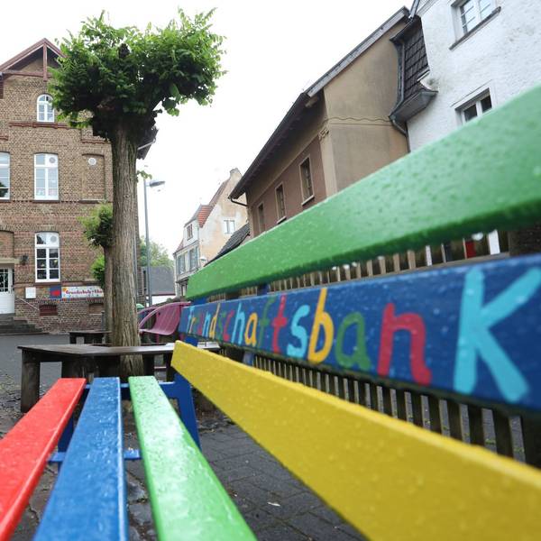 Eine bunte Sitzbank steht auf dem Schulhof.
